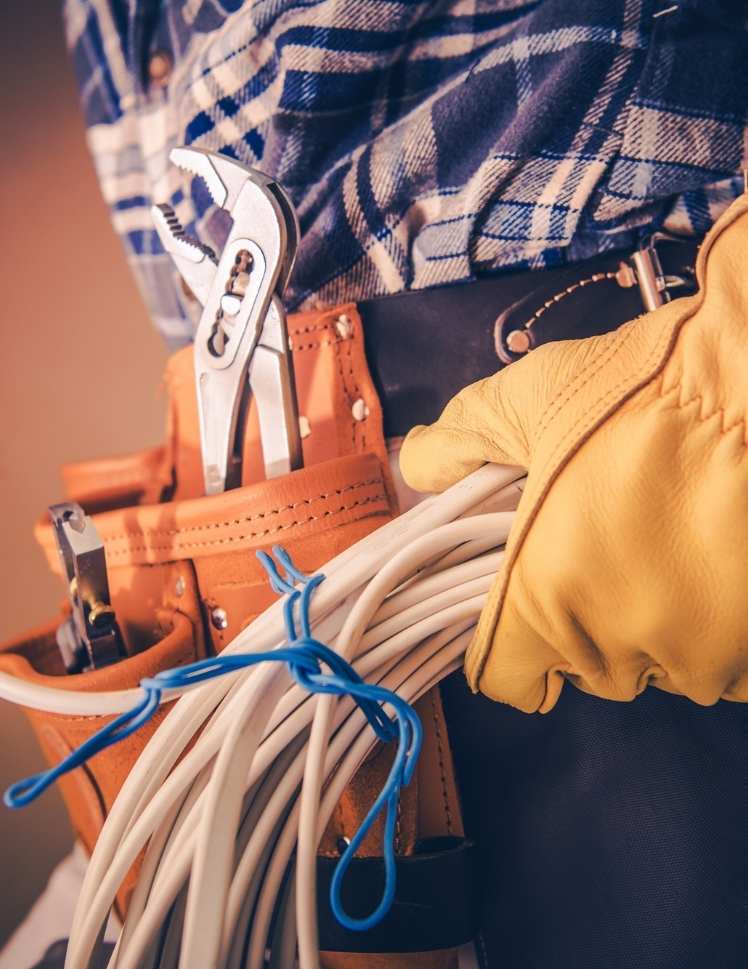 Sydney electrician wearing a toolbelt and carrying electrical cables.